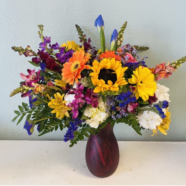 Colorful mixed bouquet with sunflowers, gerbera daisies, and alstroemeria in a red vase