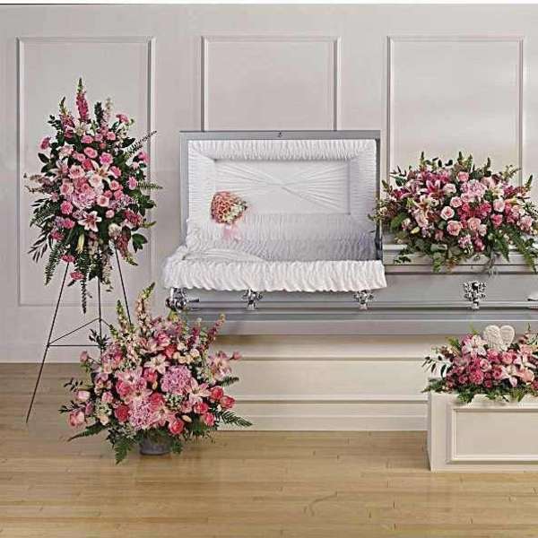 Pink floral funeral casket spray with matching standing wreaths and arrangements