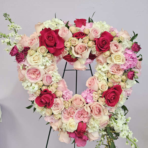 Heart-shaped floral wreath of pink and red roses on a stand