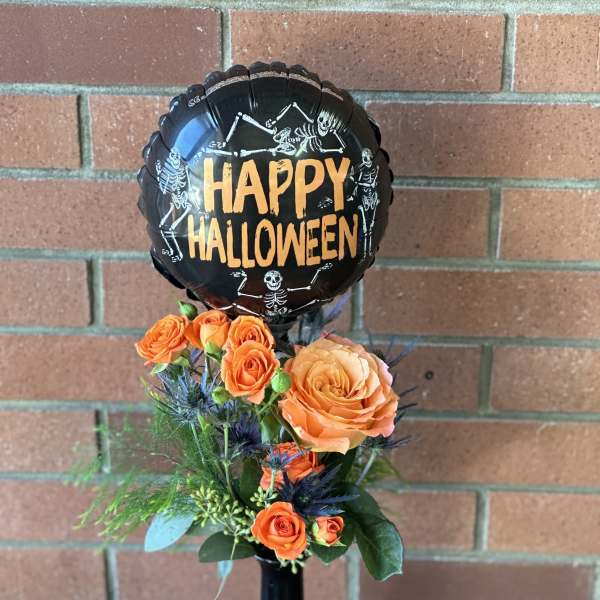 Orange roses with a Halloween balloon in a black vase