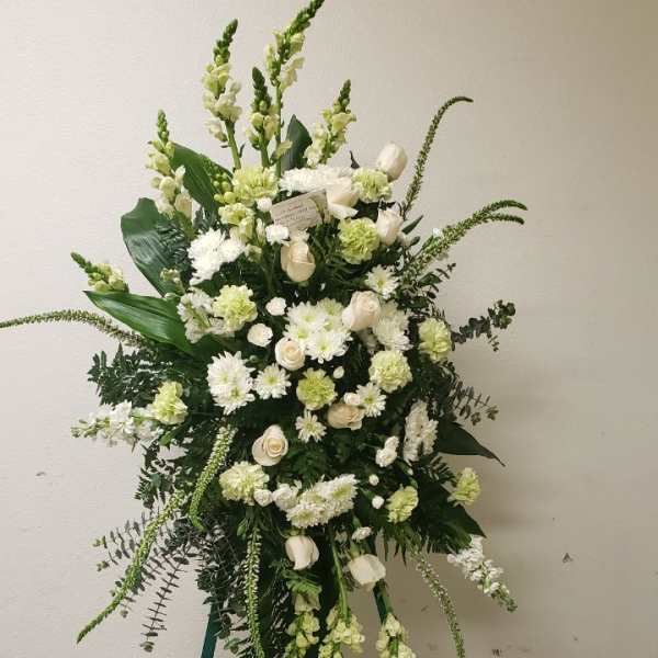 White and pale green floral standing spray on a green easel