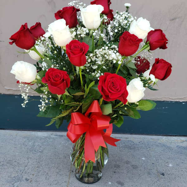 Bouquet of red and white roses in a glass vase with a red ribbon