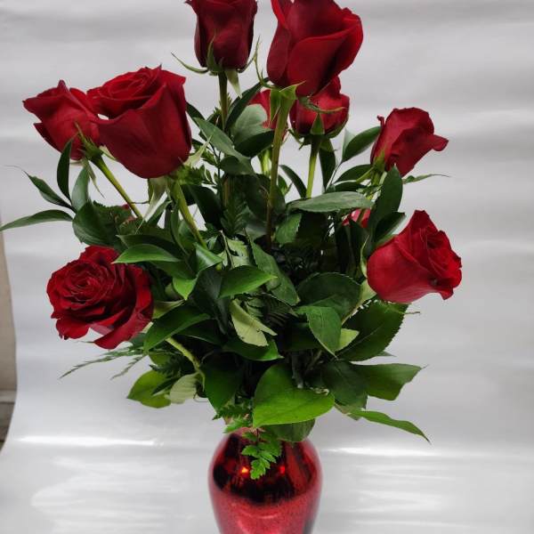 Red roses arranged in a red glass vase