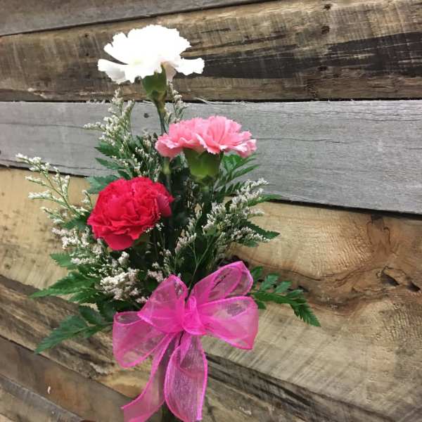 Pink and white carnations in a clear glass vase with a pink bow