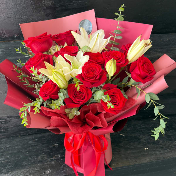 Bouquet of red roses and white lilies wrapped in pink paper