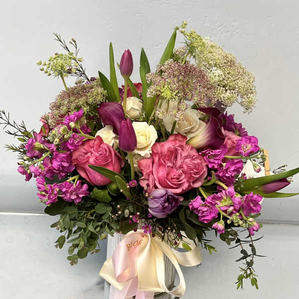 Bouquet of pink roses, purple tulips, and white calla lilies in a vase