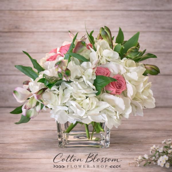 White hydrangea and pink roses in a clear glass vase