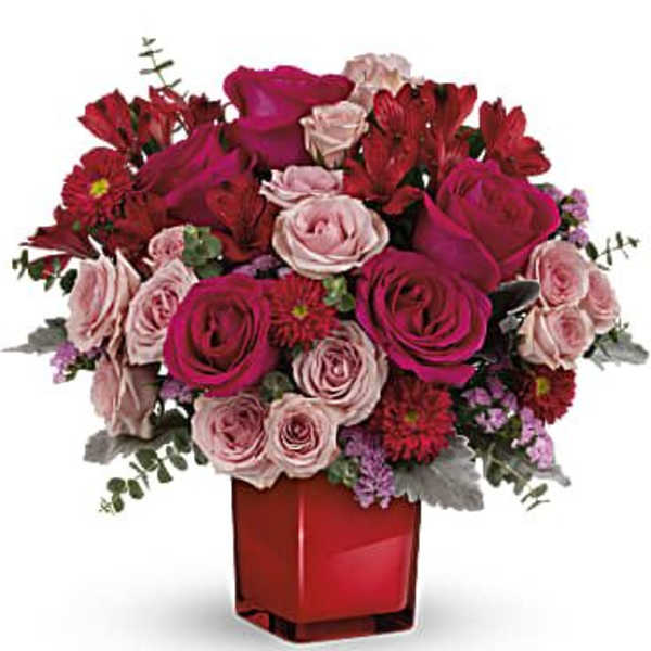 Bouquet of red and pink roses in a red glass vase