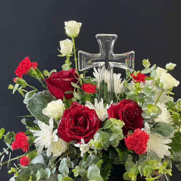 Red and white floral arrangement with a clear glass cross centerpiece