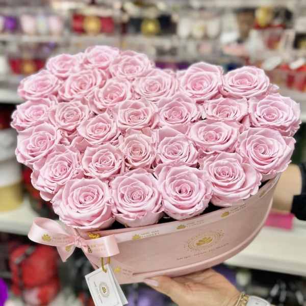 Heart-shaped arrangement of light pink roses in a pink hat box with ribbon.