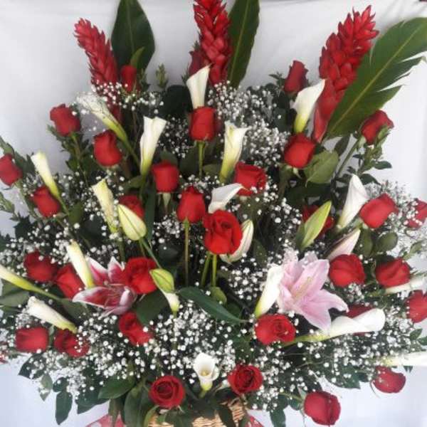 Tall basket arrangement of red roses, white calla lilies, and pink lilies with baby’s breath