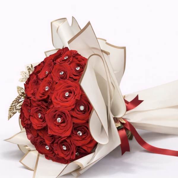 Bouquet of red roses wrapped in cream paper with a red ribbon