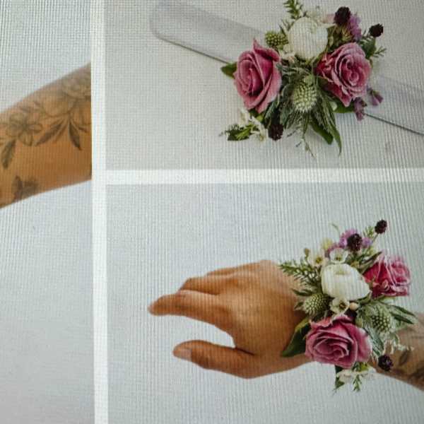 Wrist corsage with pink roses, white flowers, and greenery on a white ribbon band