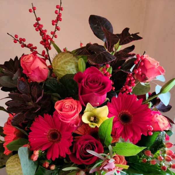 Bouquet of pink roses and red gerbera daisies in a glass vase