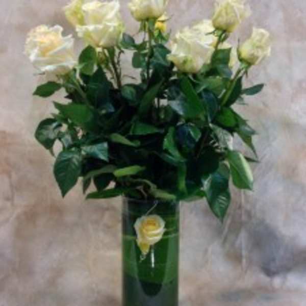 White roses in a tall green vase with a single rose on the front