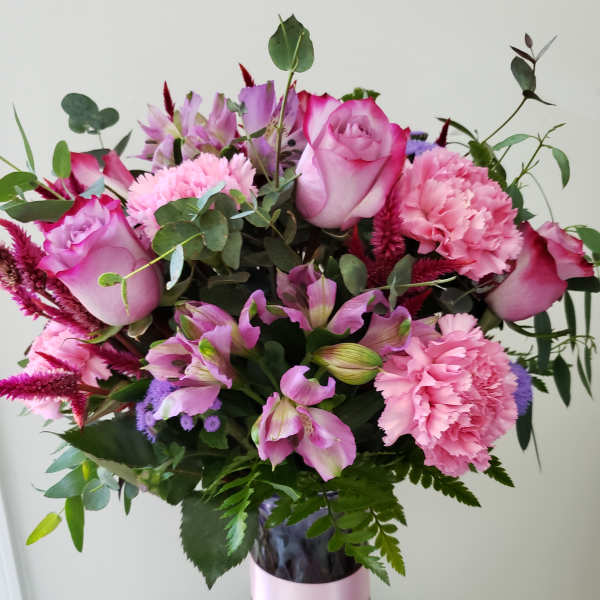 Pink roses and carnations in a purple glass vase