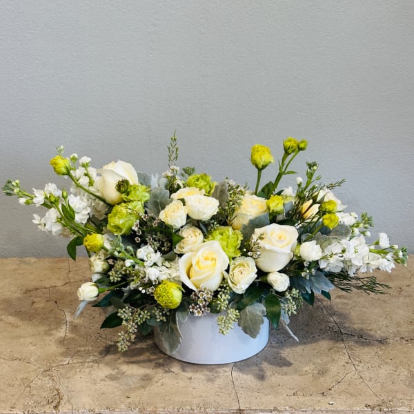 White and pale yellow rose arrangement in a low white container