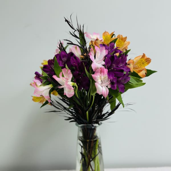Bouquet of purple, pink, and orange flowers in a clear glass vase