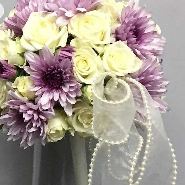 Bouquet of cream roses and lavender chrysanthemums in a glass vase with a sheer ribbon