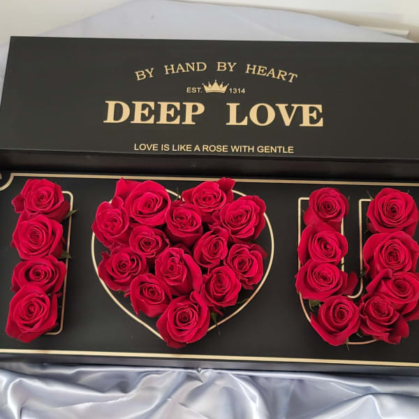 Red roses arranged to spell I LOVE U in a black gift box