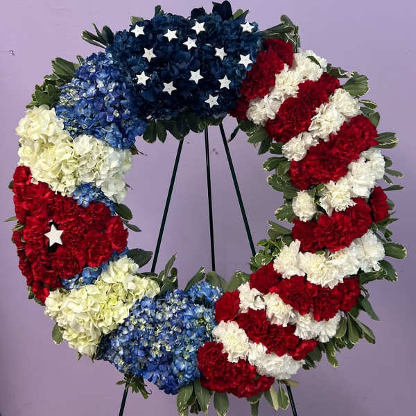 Circular floral wreath in red, white, and blue with star accents on a stand