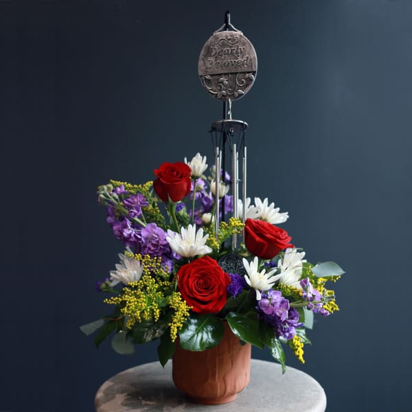 Red roses and white daisies in a pot with a "Dearly Beloved" memorial pick