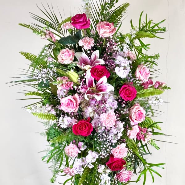 Tall standing floral spray with pink roses, lilies, and carnations on an easel