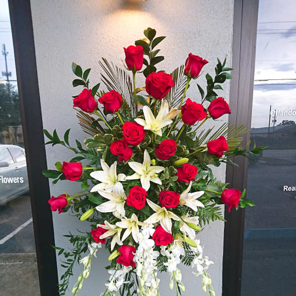 Tall standing arrangement of red roses and white lilies on an easel