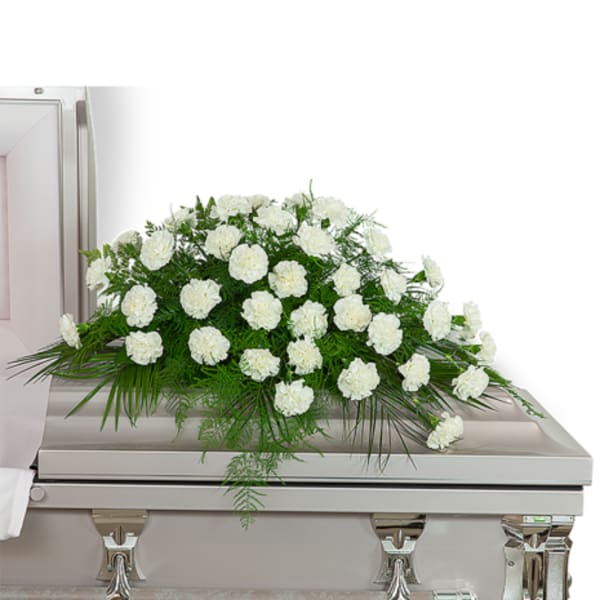 White floral spray arranged on top of a casket