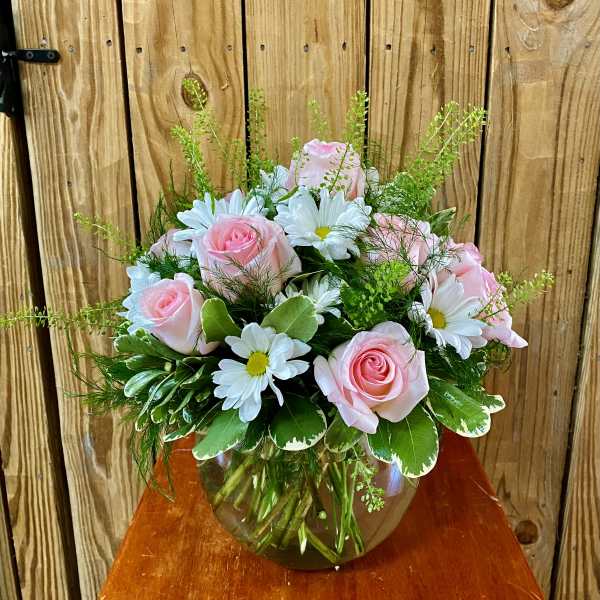 Pink roses and white daisies arranged in a glass vase