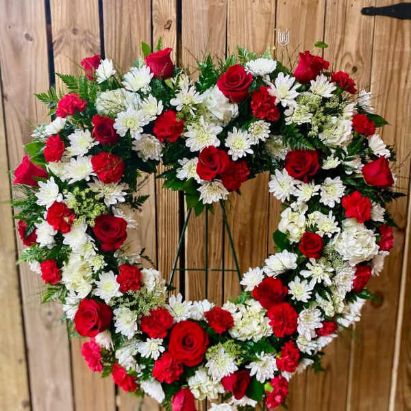 Heart-shaped wreath of red roses and white daisies on a stand