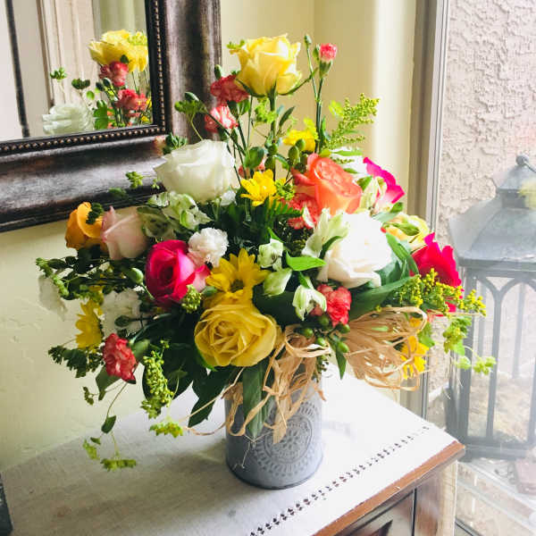 Colorful mixed flower arrangement in a metal vase on a table