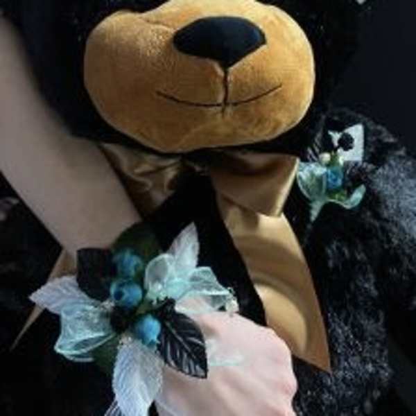 Plush teddy bear with a blue floral ribbon accessory