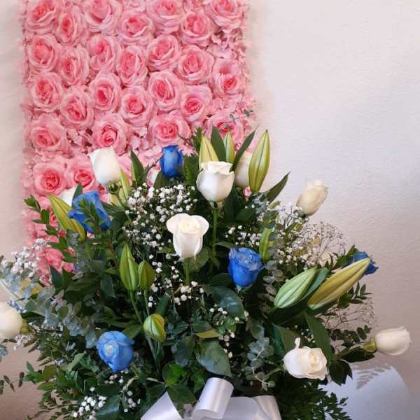 Pink rose wall backdrop behind a mixed bouquet in a vase