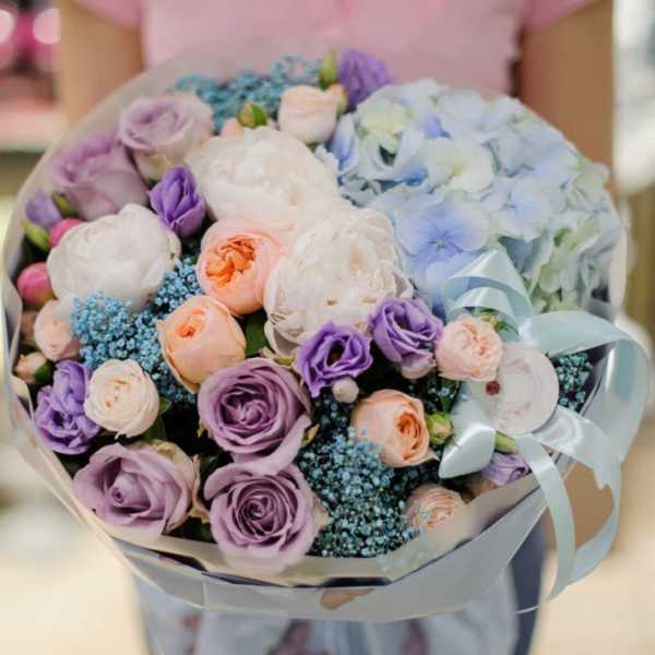 Bouquet of pastel roses and hydrangeas wrapped in pale ribbon