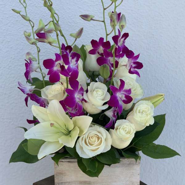 White roses and lilies with purple orchids in a wooden box