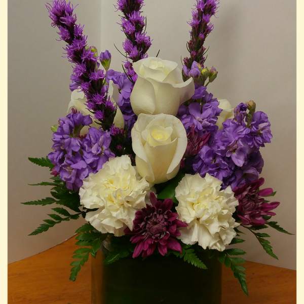 Purple and white floral arrangement in a dark vase