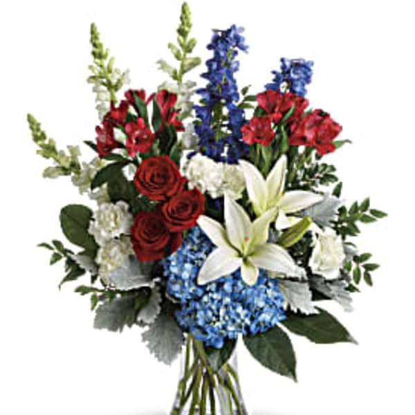 Bouquet of red roses, white lilies, and blue flowers in a glass vase