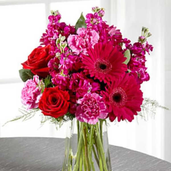 Bouquet of red roses and pink flowers in a clear glass vase