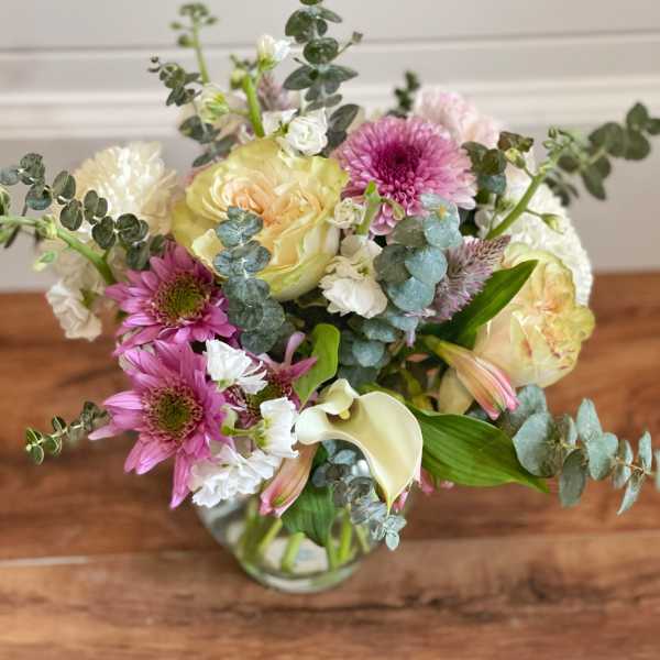 Mixed bouquet of pink and cream flowers in a glass vase