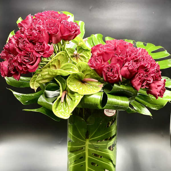 Pink rose bouquet with green anthuriums in a tall glass vase
