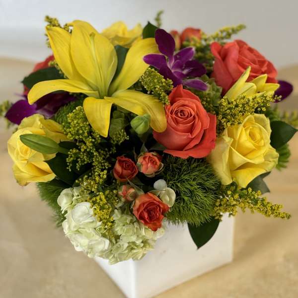 Mixed bouquet with yellow lilies, roses, and purple orchids in a white box