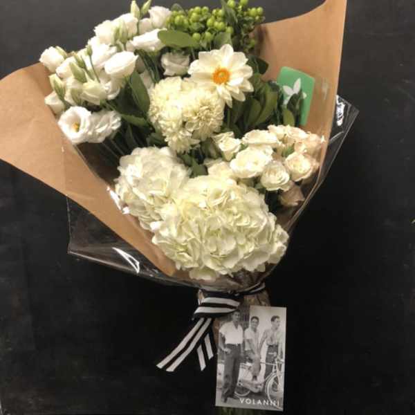 Bouquet of white flowers wrapped in brown paper with a striped ribbon