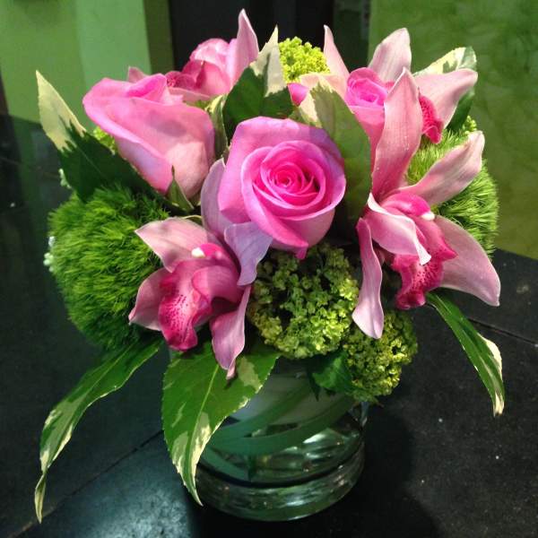 Pink roses and orchids arranged in a glass vase