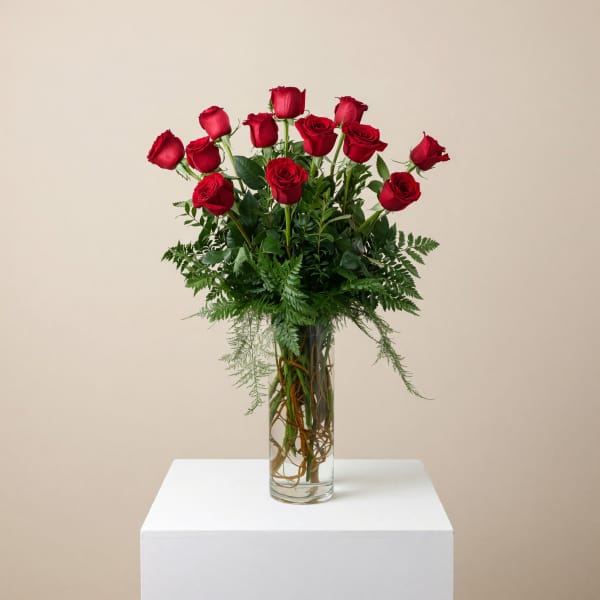 Red roses arranged in a tall clear glass vase