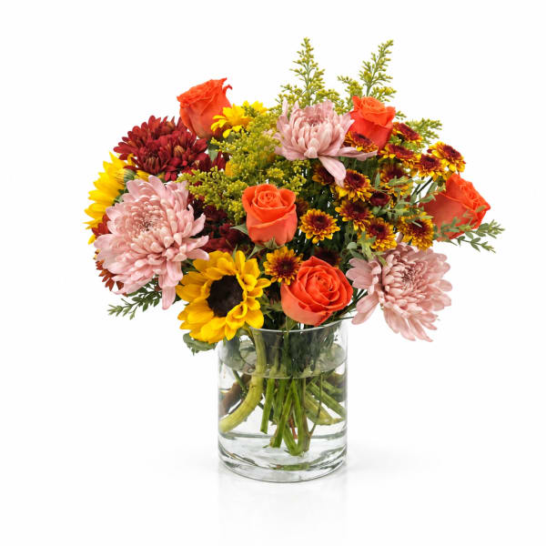 Mixed bouquet of roses, chrysanthemums, and sunflowers in a clear glass vase