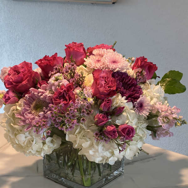 Pink and white mixed flower arrangement in a square glass vase