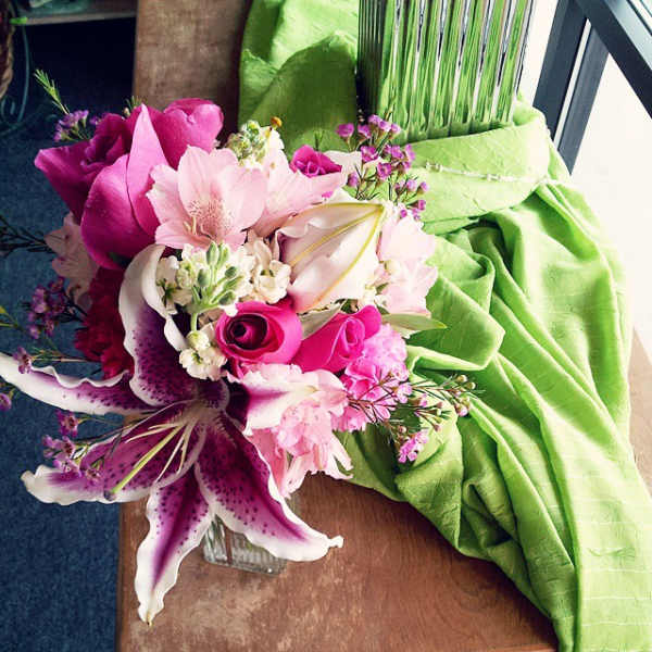 Pink and white bouquet with lilies and roses beside a green draped fabric