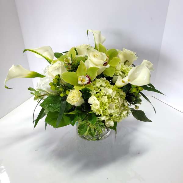 White calla lilies and roses arranged in a glass vase