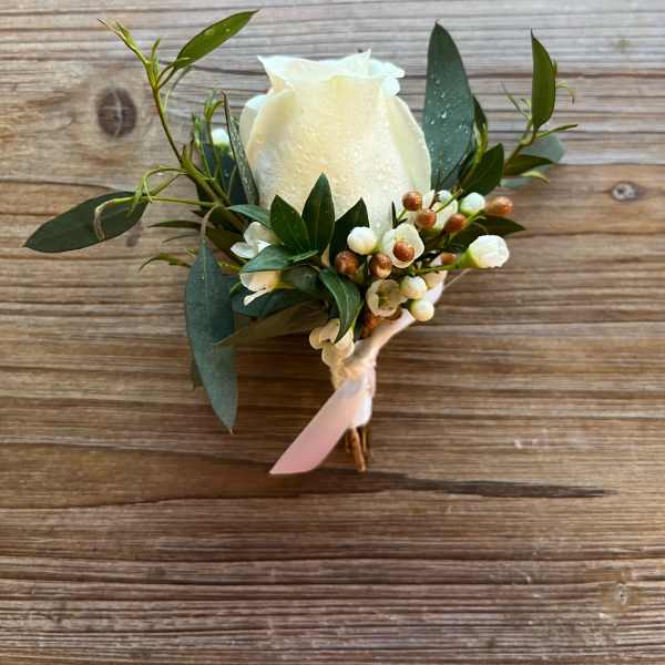 White rose boutonniere with greenery and small white berries
